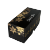 Boîte bûche noire avec motifs dorés vue de 3/4.
